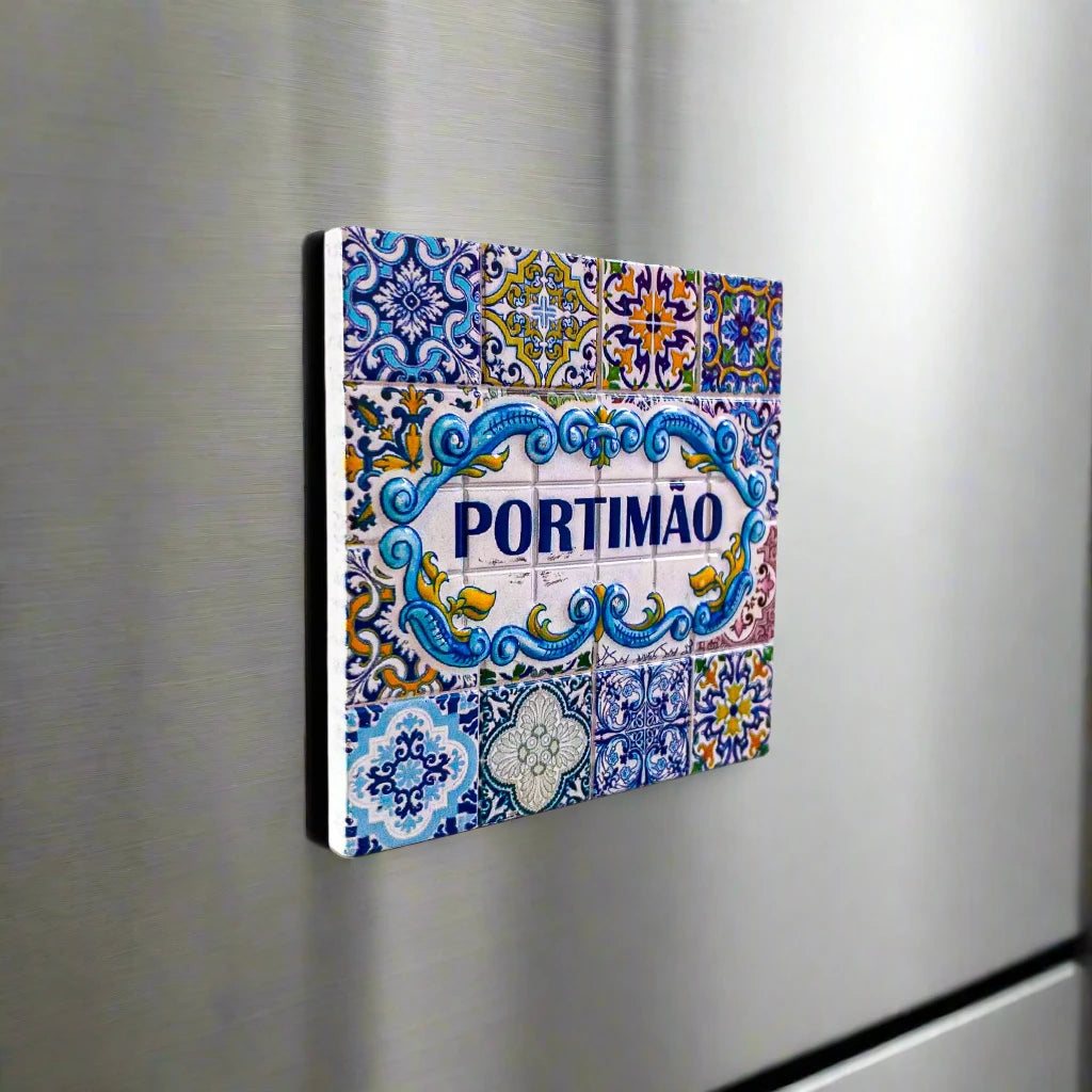 A square Portuguese ceramic tile with detailed blue, yellow, and white patterns, showcasing the name "PORTIMÃO" in bold blue letters at the center. Surrounding it are intricate floral and geometric designs, reflecting the traditional Azulejo style from Portugal's Algarve region—a stunning piece of craftsmanship.