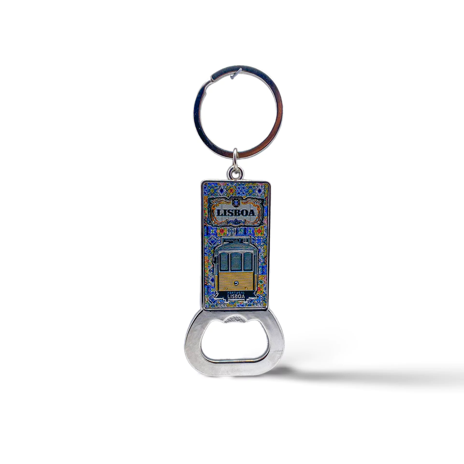 A metal keychain featuring a bottle opener at the bottom and a rectangular enamel tile at the top with a depiction of a Lisbon tram. The word "Lisboa" is written above the tram, surrounded by a decorative blue and yellow border, capturing the charm of Portugal.