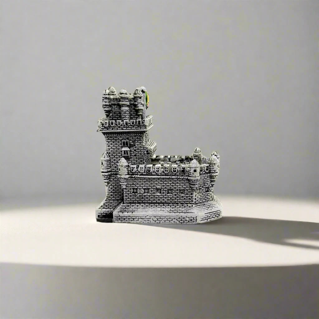 This miniature replica of the Belem Tower from Lisbon, Portugal, features fine detailing and the word "PORTUGAL" in gold at its base. The tower is isolated against a white background, highlighting its craftsmanship.