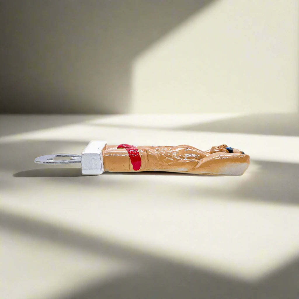A novelty bottle opener adorned with a figure of a muscular man wearing red swim briefs and sunglasses, standing with his hands behind his head. A quirky and unique keepsake from Portugal.