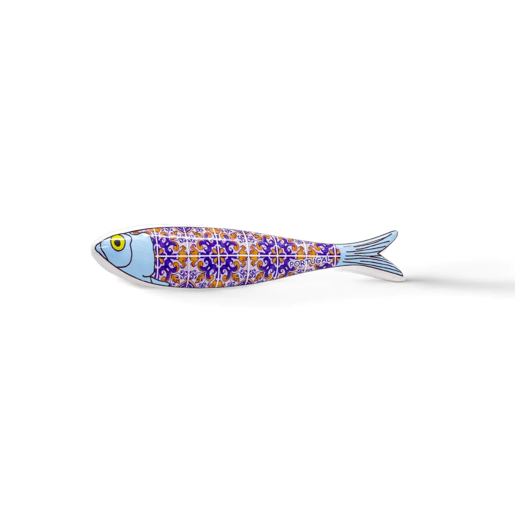 A small, fish-shaped ceramic object resembling a sardine, adorned with intricate purple and orange tile-like patterns on its body, a light blue head, and a yellow eye. This charming souvenir is isolated on a plain white background.