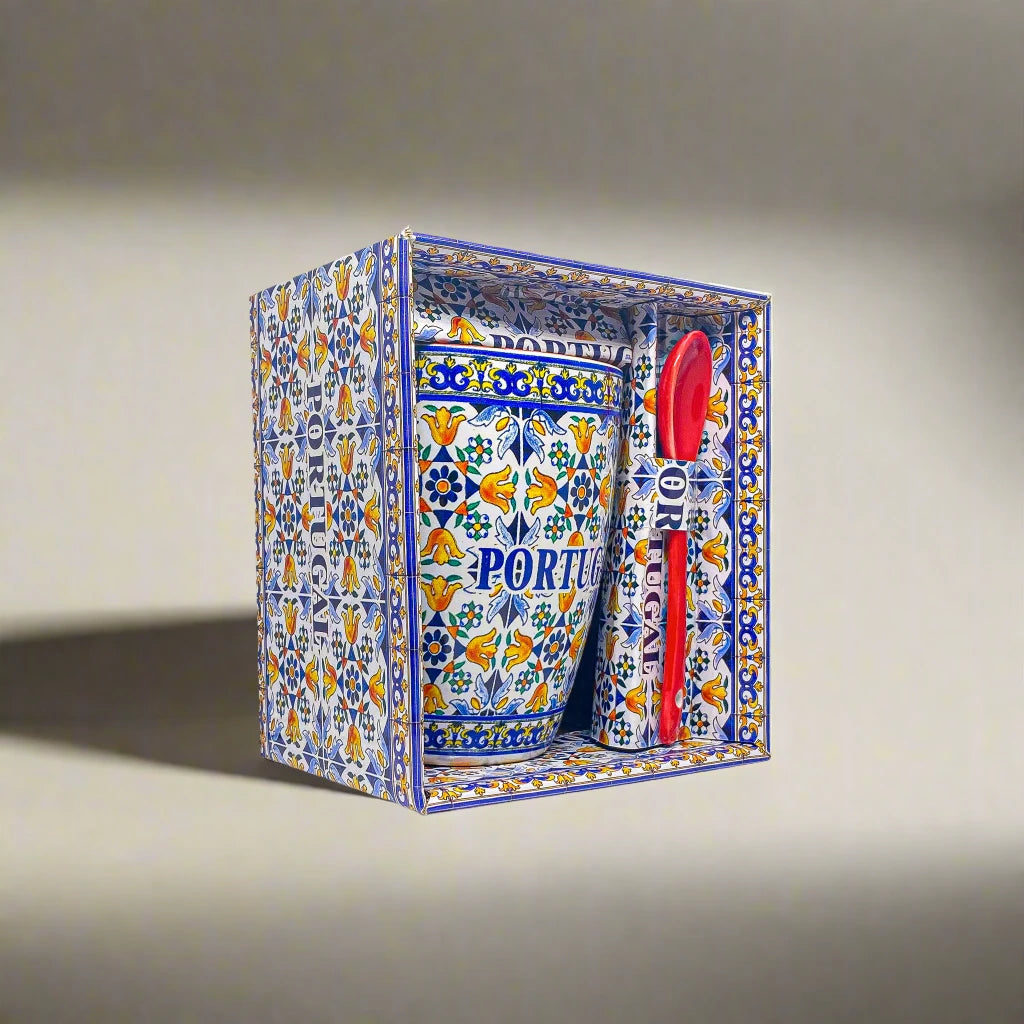 A decorative ceramic coffee mug and spoon set packaged in an ornate box with traditional Portuguese patterns and designs. The mug prominently features the word "PORTUGAL" along with floral and geometric motifs, matching the decorative style of the box.