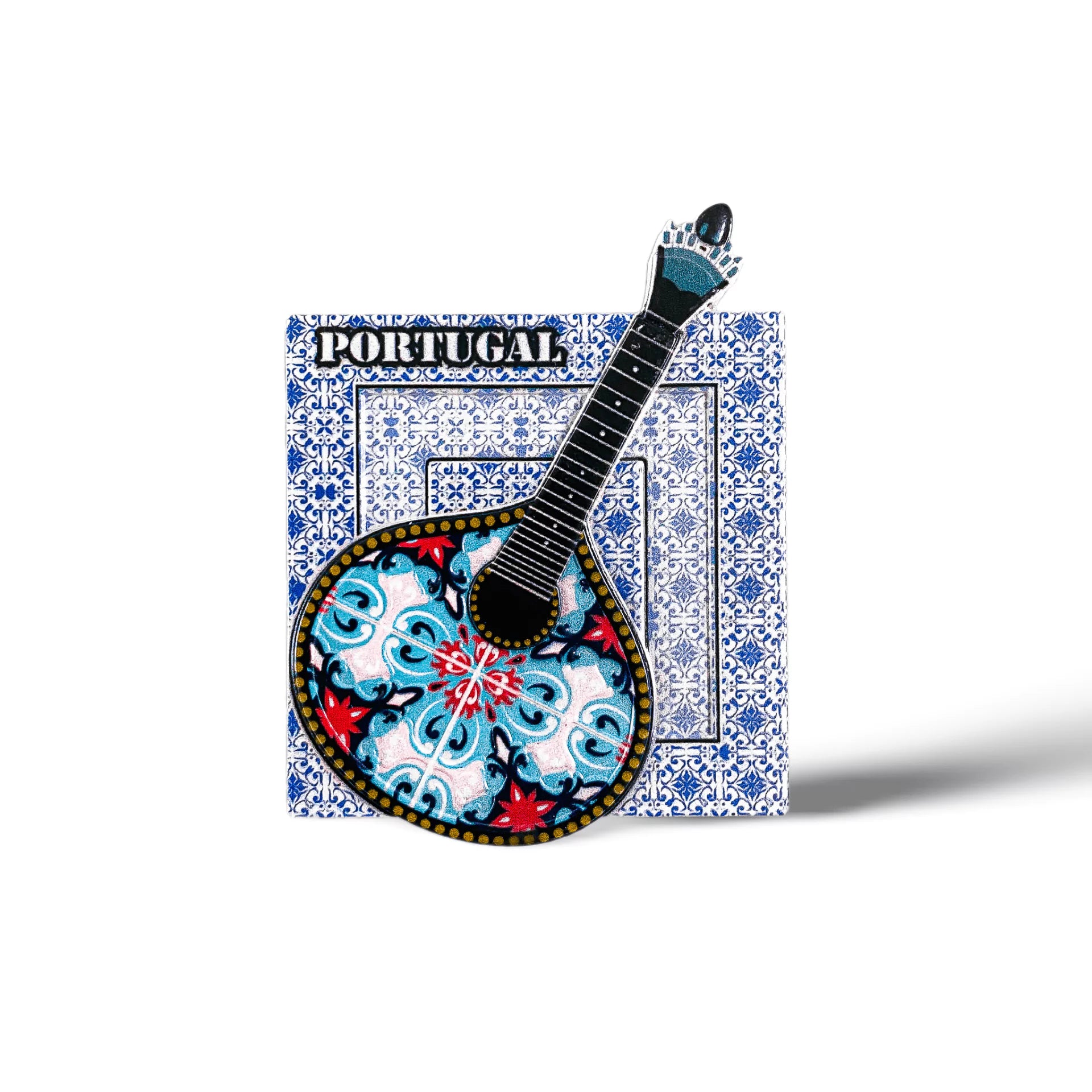A magnet featuring the word "Portugal" at the top, with a traditional Portuguese "guitarra classica" at its center. The guitar showcases an ornate, colorful design with blue, red, and black patterns. The backdrop consists of a white square adorned with intricate blue tile patterns.