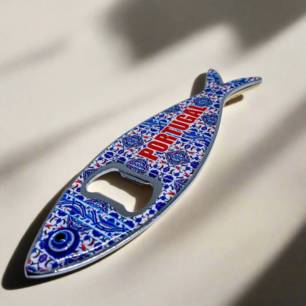 A fish-shaped metal bottle opener with intricate, vibrant patterns and the word "PORTUGAL" featured in blue on the body. This unique souvenir also serves as a magnet, perfect for keeping on your fridge as a reminder of Portugal.