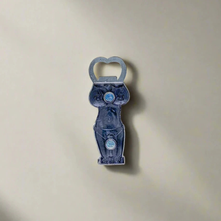 This metallic bottle opener features a Portuguese girl in a kneeling pose, her hands behind her head. Her bikini is adorned with the national colors and emblem of Portugal, and "Portugal" is written prominently at the top. A magnet on the back adds functionality for easy placement on metal surfaces.