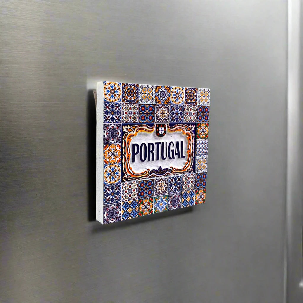 A decorative ceramic tile magnet adorned with intricate, vibrant patterns, featuring the word "Portugal" in bold blue letters at the center. Framed by ornate yellow and blue designs, this piece beautifully captures the traditional Portuguese azulejos art style, making it an ideal souvenir from Portugal.