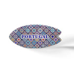 This oval-shaped ceramic object features a colorful mosaic pattern inspired by traditional Portuguese azulejo tiles. The word "PORTUGAL" is prominently written in blue uppercase letters in the center. It sits on a cork base, casting a soft shadow on the white surface.