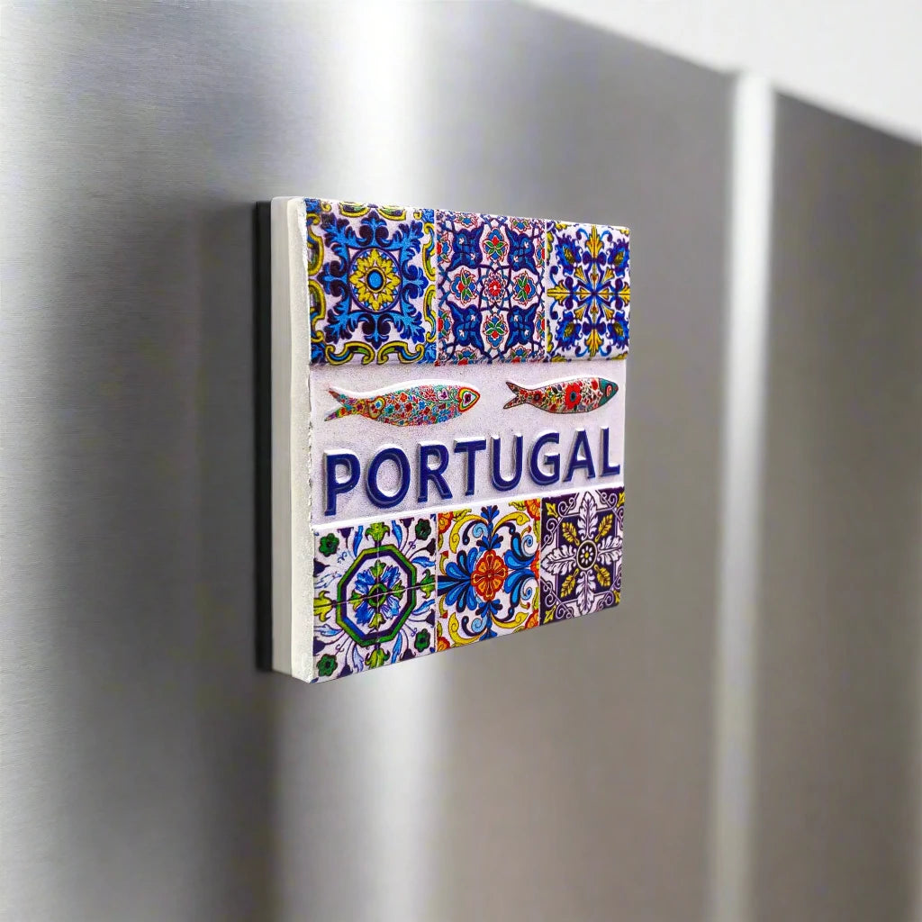 A decorative square magnet showcasing traditional Portuguese tile designs with vibrant, intricate patterns. At the center, the word "PORTUGAL" appears in bold blue text, accompanied by two stylized fish illustrations above it. This charming magnet is an ideal souvenir, capturing the essence of Portugal's rich cultural heritage.