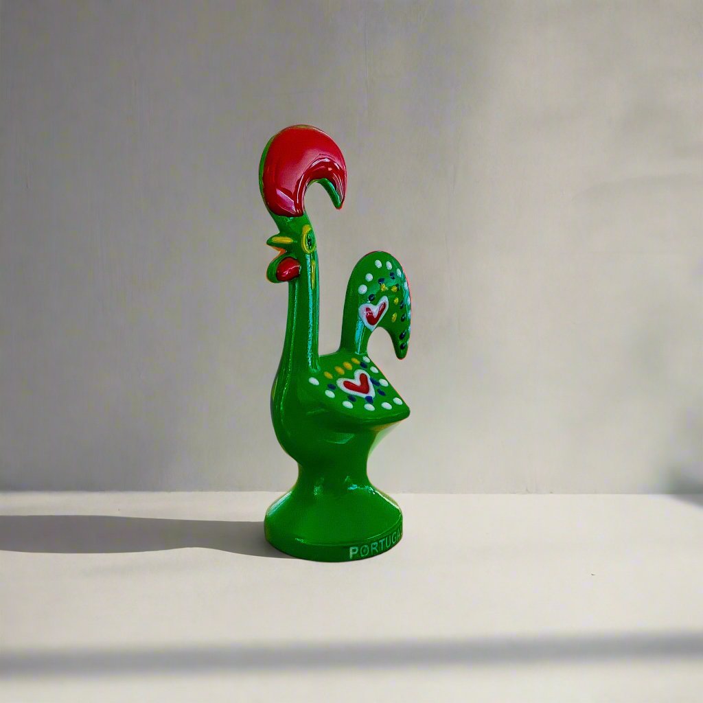 A decorative green and red rooster figurine, symbolizing the Galo de Barcelos from Portugal, set against a white surface.