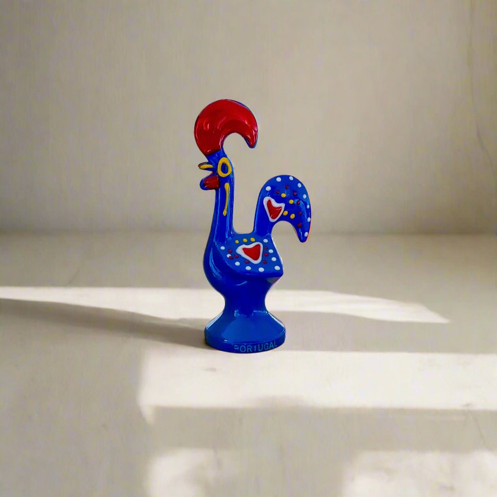 A colorful blue and red rooster figurine, showcasing the Galo de Barcelos, a cherished souvenir from Portugal.
