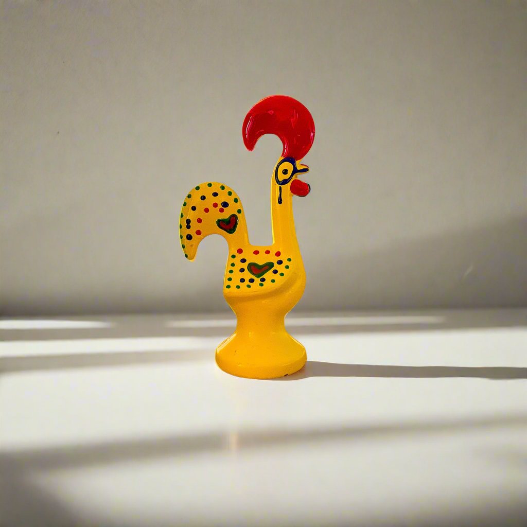 A yellow ceramic rooster, reminiscent of the Galo de Barcelos, a popular souvenir from Portugal.