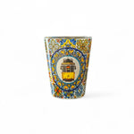 A shot glass with a colorful traditional azulejo tile design featuring a yellow portuguese tram.