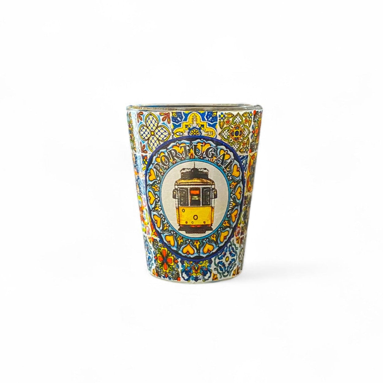 A shot glass with a colorful traditional azulejo tile design featuring a yellow portuguese tram.