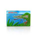 A colorful fridge magnet featuring a panoramic view of a coastal landscape with traditional red fishing boats, green hills, tropical vegetation, and the ocean, with the word 'MADEIRA' prominently displayed.