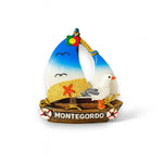 A colorful fridge magnet shaped like a sailboat with beach and seagull elements, and the text 'Monte Gordo' displayed.