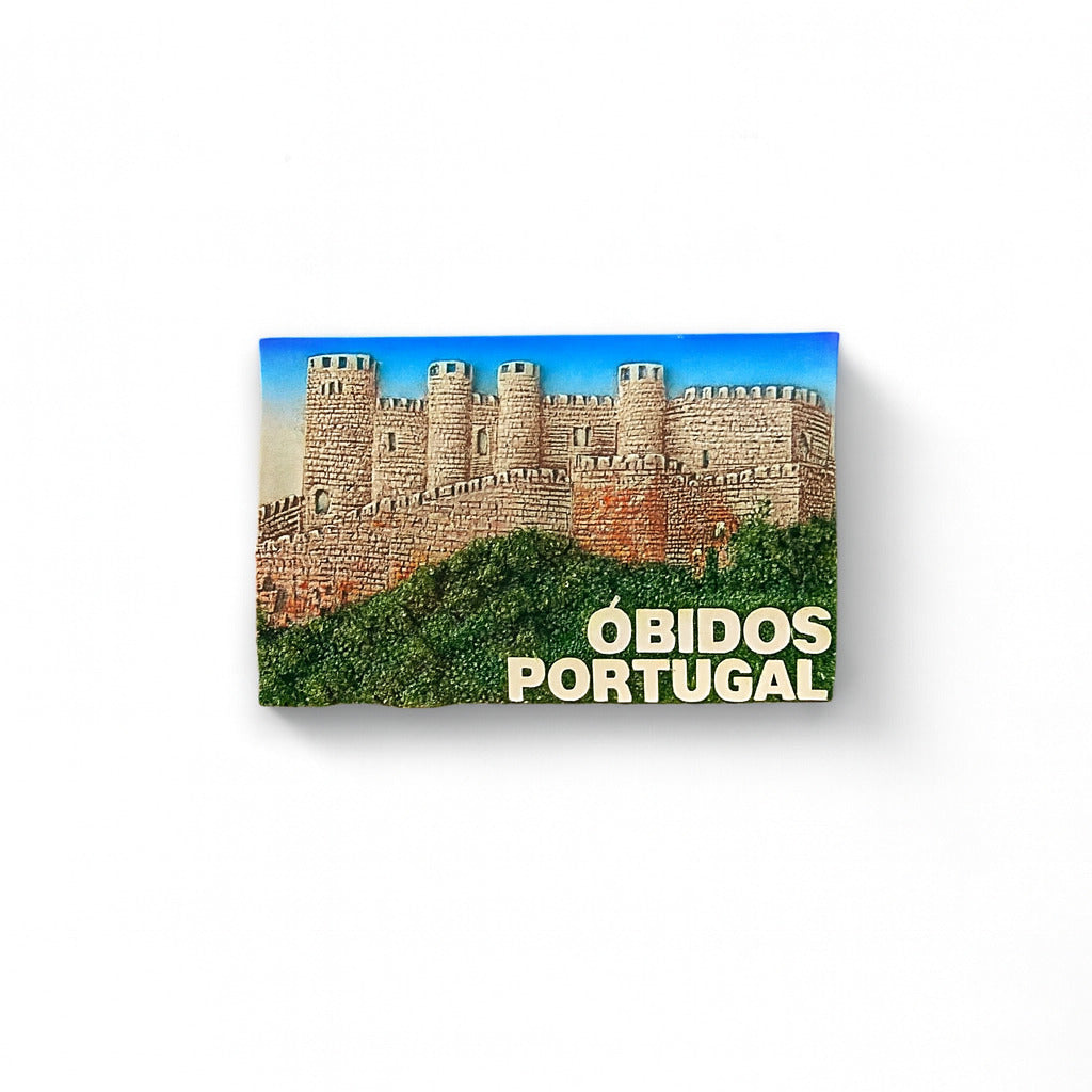 A 3D relief fridge magnet featuring the medieval castle of Óbidos in Portugal, with blue sky and greenery in the background.