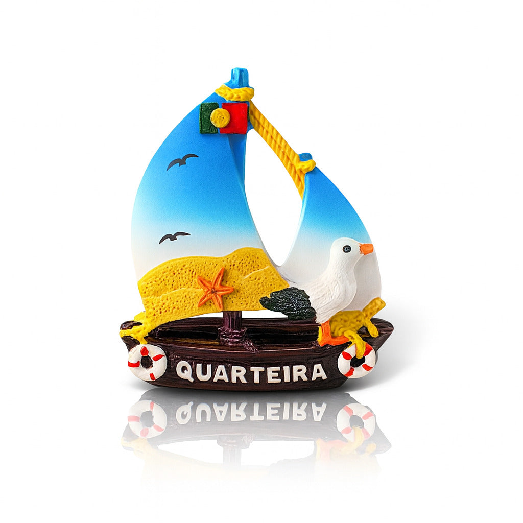A colorful fridge magnet in the shape of a sailboat with beach-themed elements, including a representation of the Portuguese flag and the word 'Quarteira' displayed.