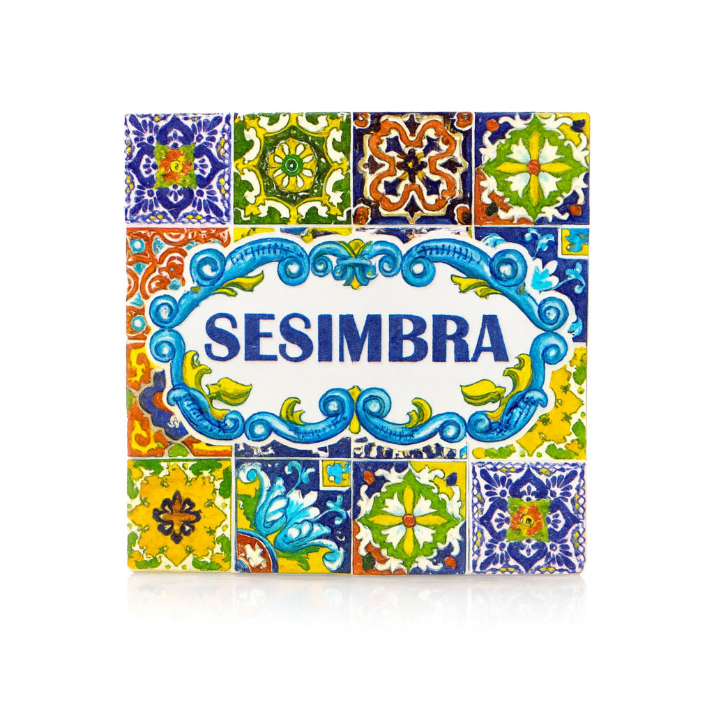 Square magnet with the name "Sesimbra" in blue letters, surrounded by traditional Portuguese azulejo tile patterns in bright colors, reflecting the town’s cultural style