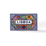 A rectangular ceramic tile with brightly colored geometric and floral patterns, predominantly in blue, red, yellow, and green. The center features the word "LISBOA" in bold blue letters on a white background, surrounded by intricate decorative designs. Perfect as a Lisbon souvenir magnet.