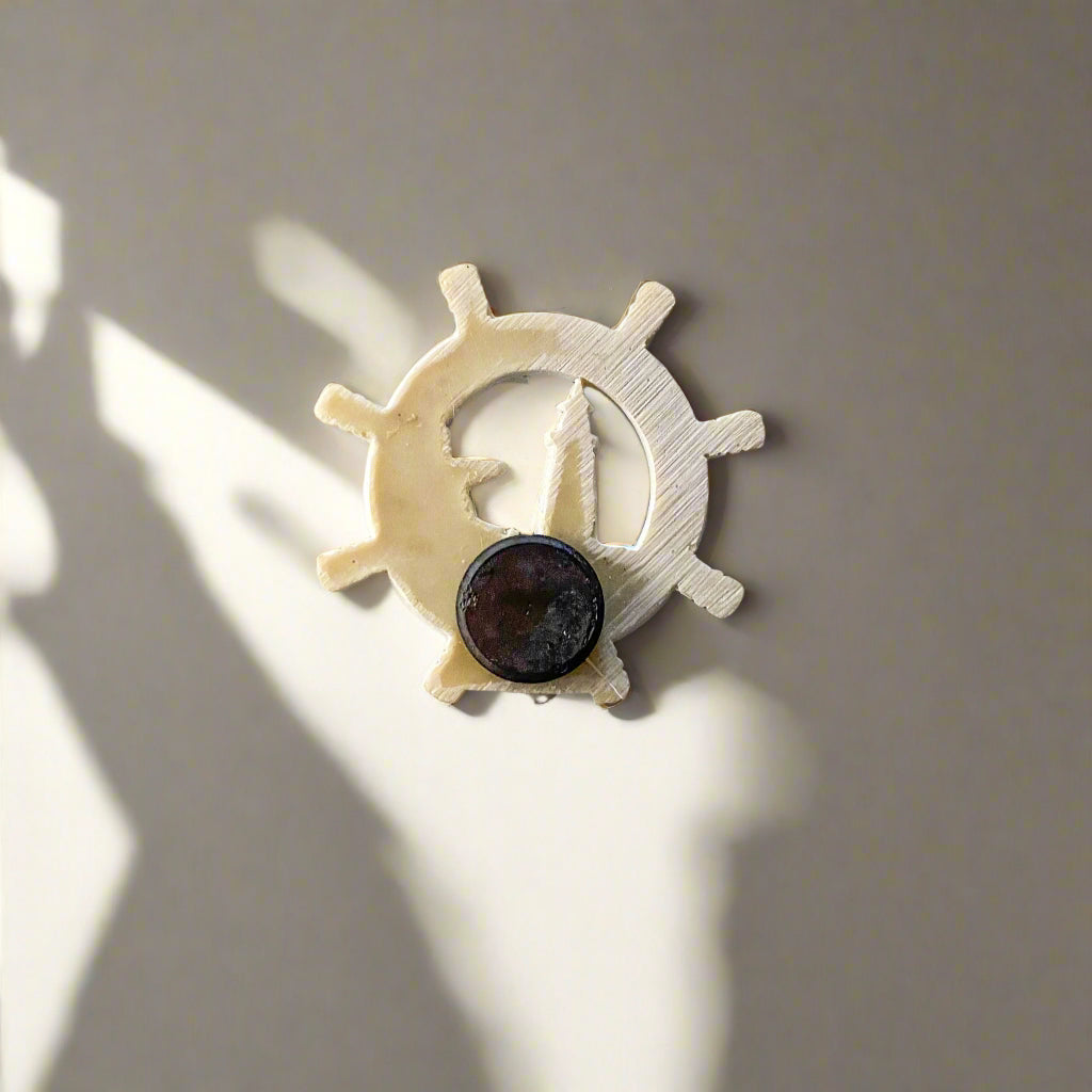 Back side of a souvenir magnet from Olhão, Portugal, shaped like a ship's wheel with a round black magnet in the center