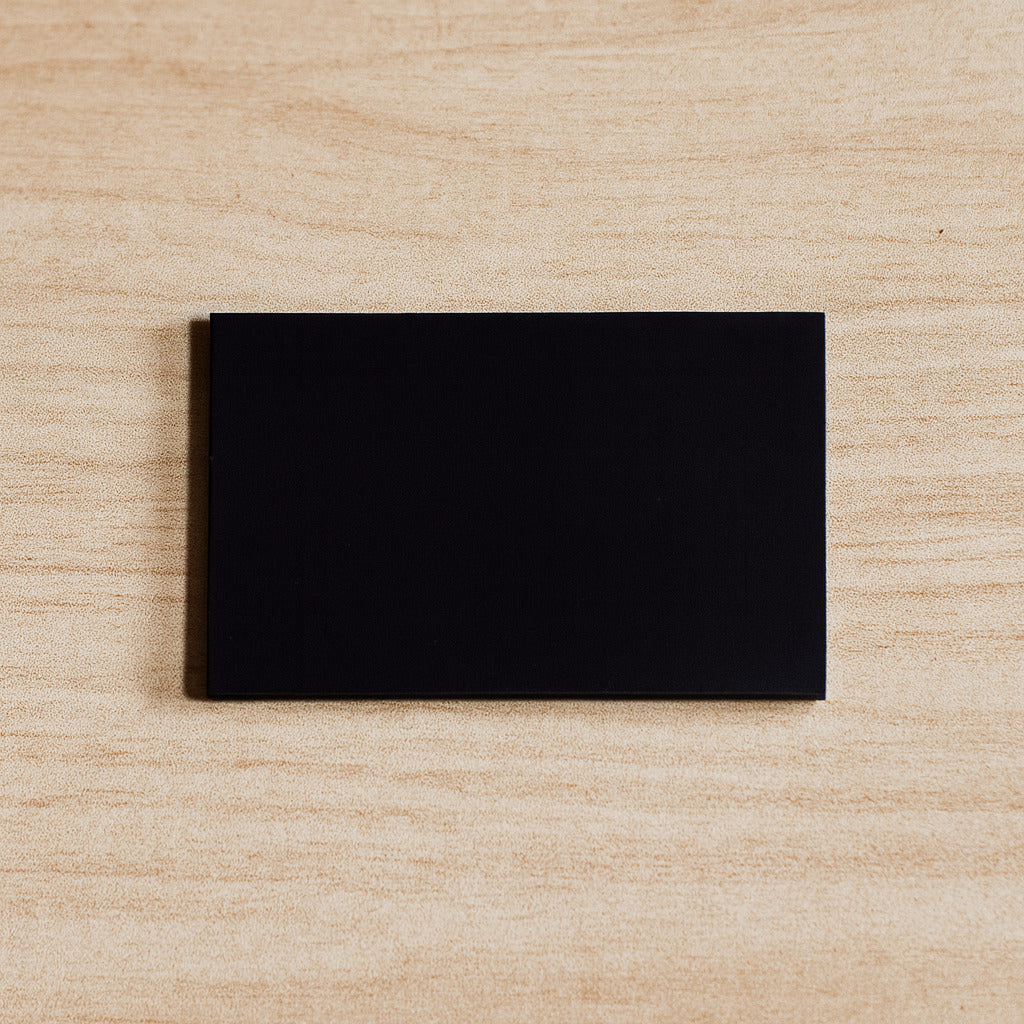 Black rectangular magnet on a beige wooden surface