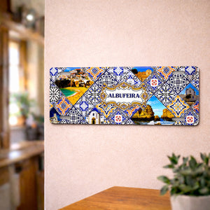 Albufeira metal souvenir sign mounted on a wall featuring coastal cliffs, beaches and traditional Portuguese azulejos patterns