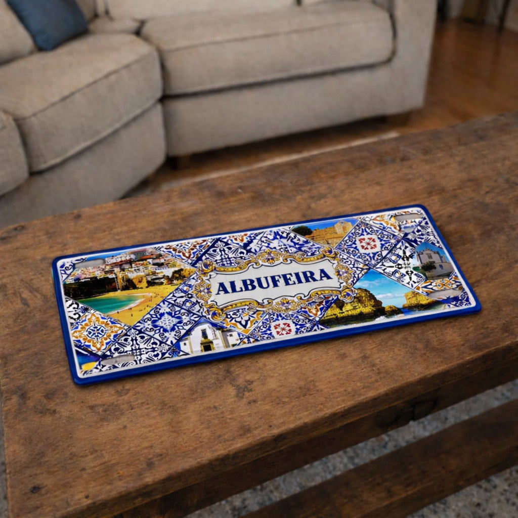 Albufeira metal souvenir sign placed on a wooden table showing beach scenery, cliffs and classic Portuguese tile design