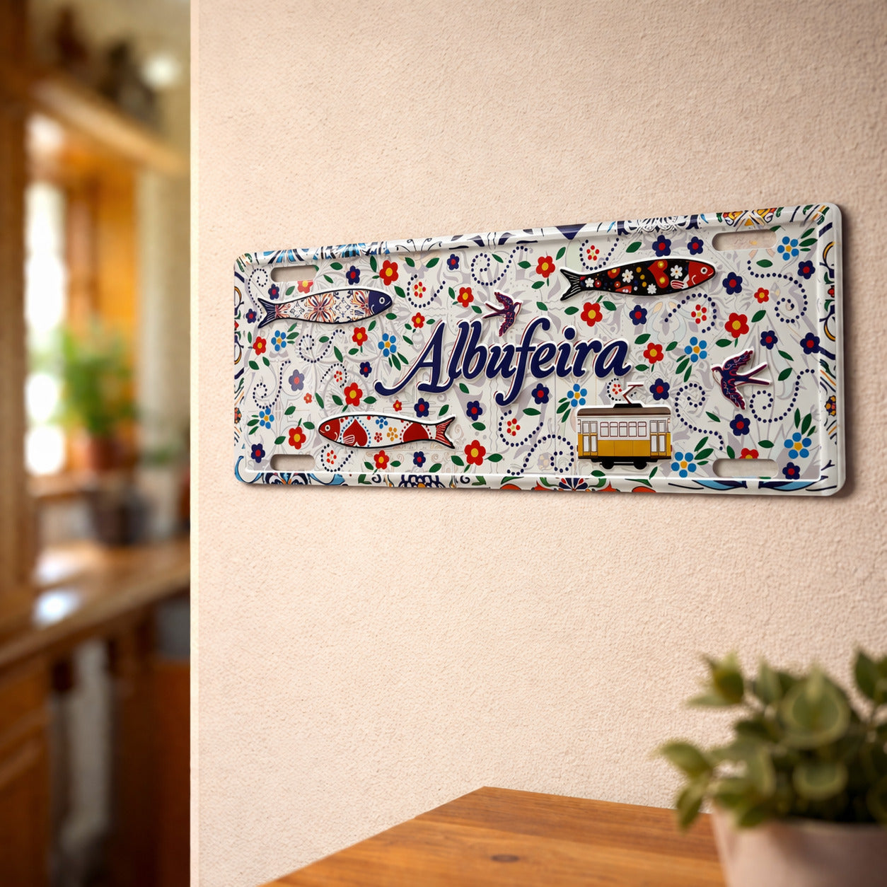 Albufeira metal souvenir sign mounted on a wall featuring colorful floral patterns, decorative sardines and a traditional tram