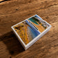 Albufeira souvenir playing card box on a rustic wooden table with Algarve beach design on the cover.
