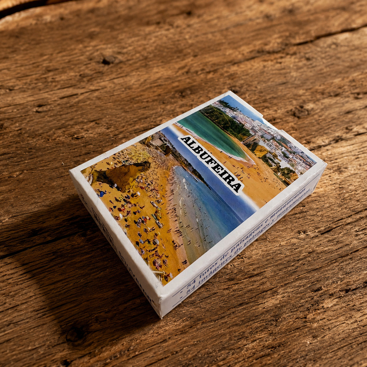 Albufeira souvenir playing card box on a rustic wooden table with Algarve beach design on the cover.