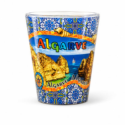 Algarve Portugal souvenir shot glass with coastal landscape illustration, blue Portuguese azulejo patterns, and ocean scenery isolated on white background.