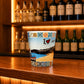 Algarve souvenir shot glass featuring coastal beach scenery and colorful Portuguese azulejo tile patterns displayed on a wooden counter