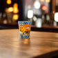 Portugal Algarve shot glass featuring iconic rock formations, ocean views, and traditional azulejo-inspired artwork in a warm bar setting.
