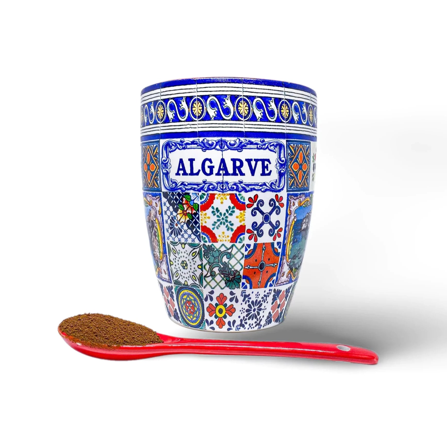 A colorful Algarve ceramic cup with geometric patterns, labeled as an Algarve Mug with Regional Design - Perfect for Coffee or Display, is placed beside a red spoon holding ground coffee on a white background.