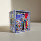 A colorful ceramic coffee mug with intricate patterns and "ALGARVE" text is displayed in a matching decorative box. A red spoon is attached to the set. The box and mug feature a vibrant mosaic design, inspired by Portugal's rich artistry, creating a traditional and artistic appeal.