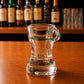 Side profile of Algarve flamingo tropical bikini style shot glass with green tropical leaf artwork and pink flamingo illustrations on wooden bar counter.