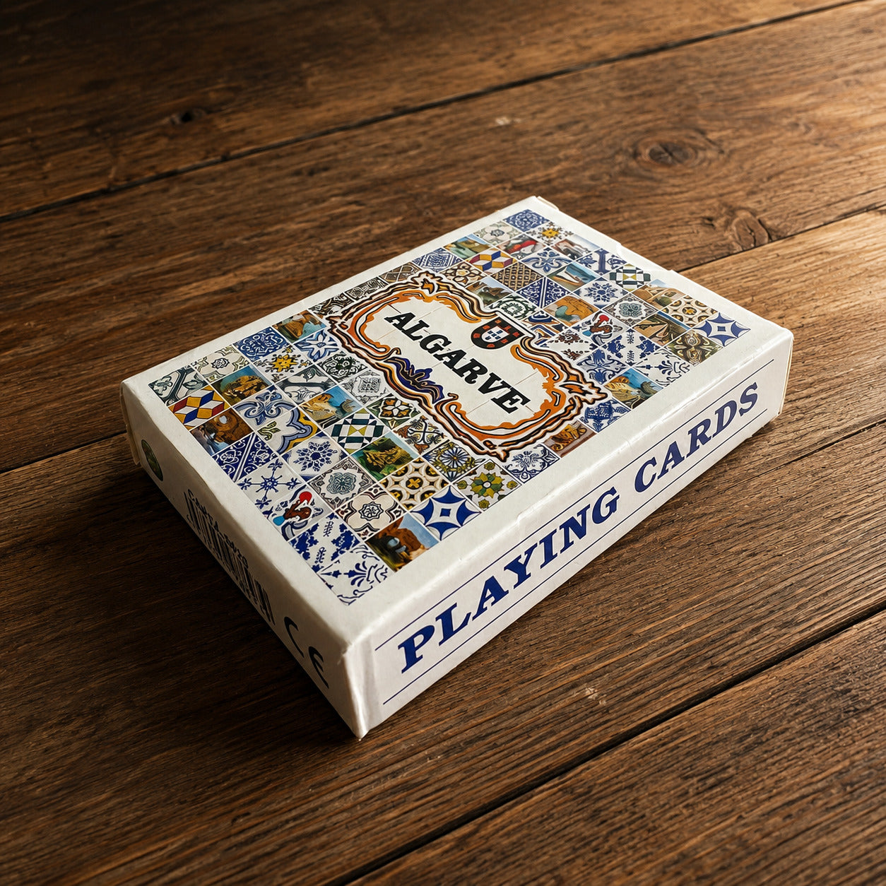 Algarve souvenir playing cards box displayed on a wooden table, with colourful Portuguese tile artwork and playing cards text on the side.