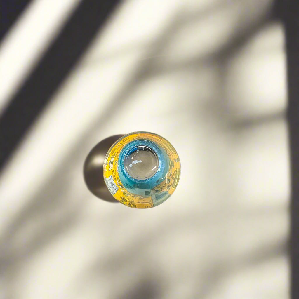 Top view of Algarve Portugal souvenir shot glass featuring colorful illustrated map artwork with soft natural shadows.