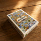Algarve playing cards souvenir box with traditional Portuguese tile design, photographed on a rustic wooden table with warm natural light.