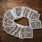 Algarve playing cards souvenir deck spread in a circular arrangement on a rustic wooden table, featuring Portuguese tile-inspired card backs.