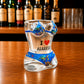 Angled front view of Algarve sea turtle ocean bikini style shot glass featuring marine life illustrations, sea turtles, underwater artwork, and I Love Algarve text on wooden surface.