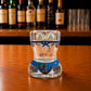 Back view of Algarve sea turtle ocean bikini style shot glass with blue underwater artwork, sea turtle illustrations, and decorative marine design on wooden bar counter.
