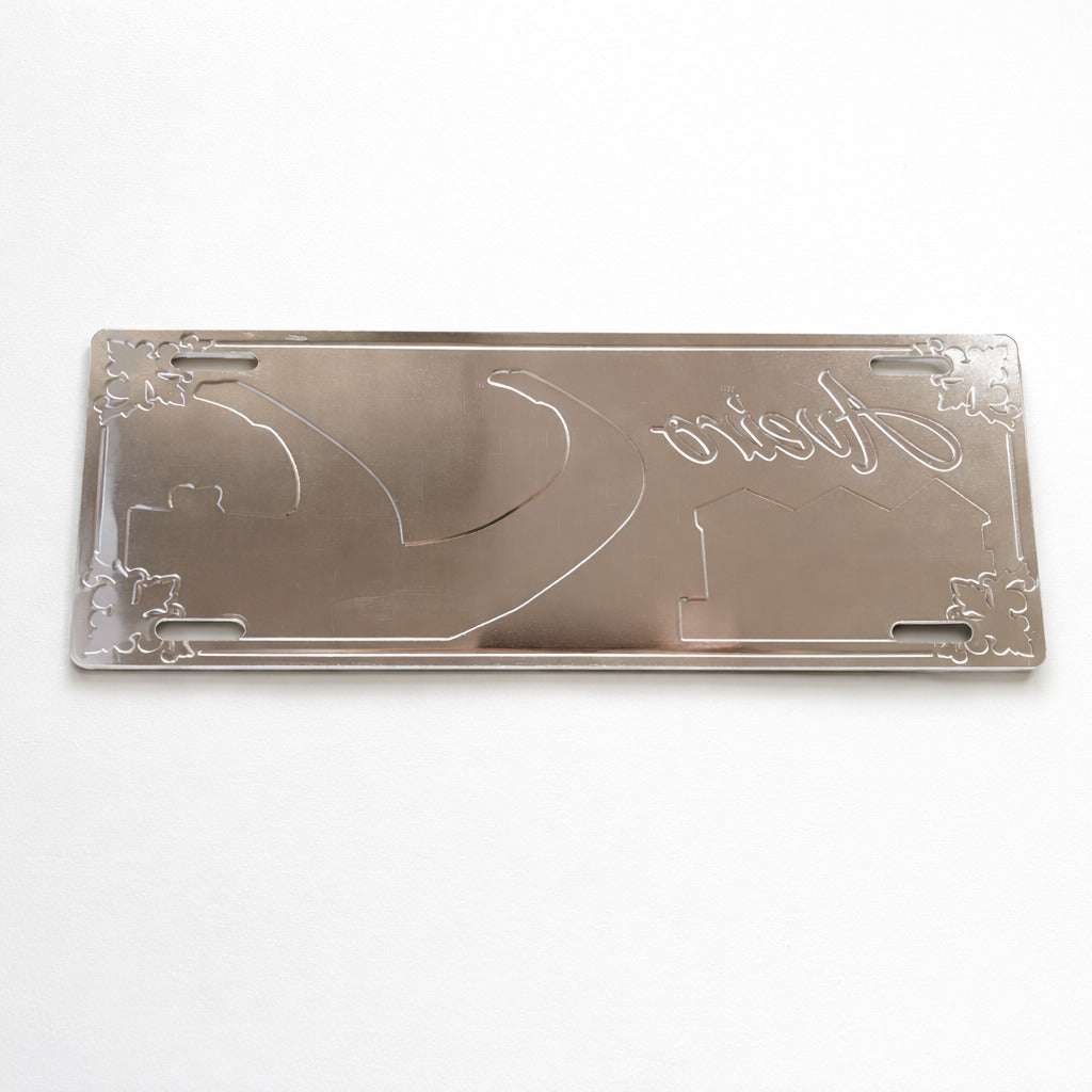 Backside of Aveiro metal souvenir sign showing engraved outlines of boats and buildings on a metallic surface