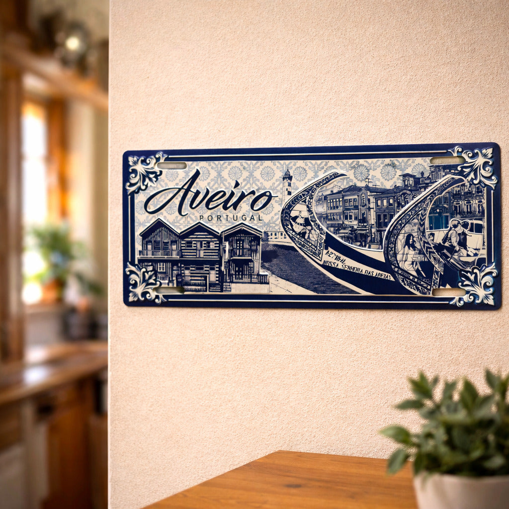 Aveiro metal souvenir sign mounted on a wall featuring moliceiro boats, traditional houses and blue azulejos style design