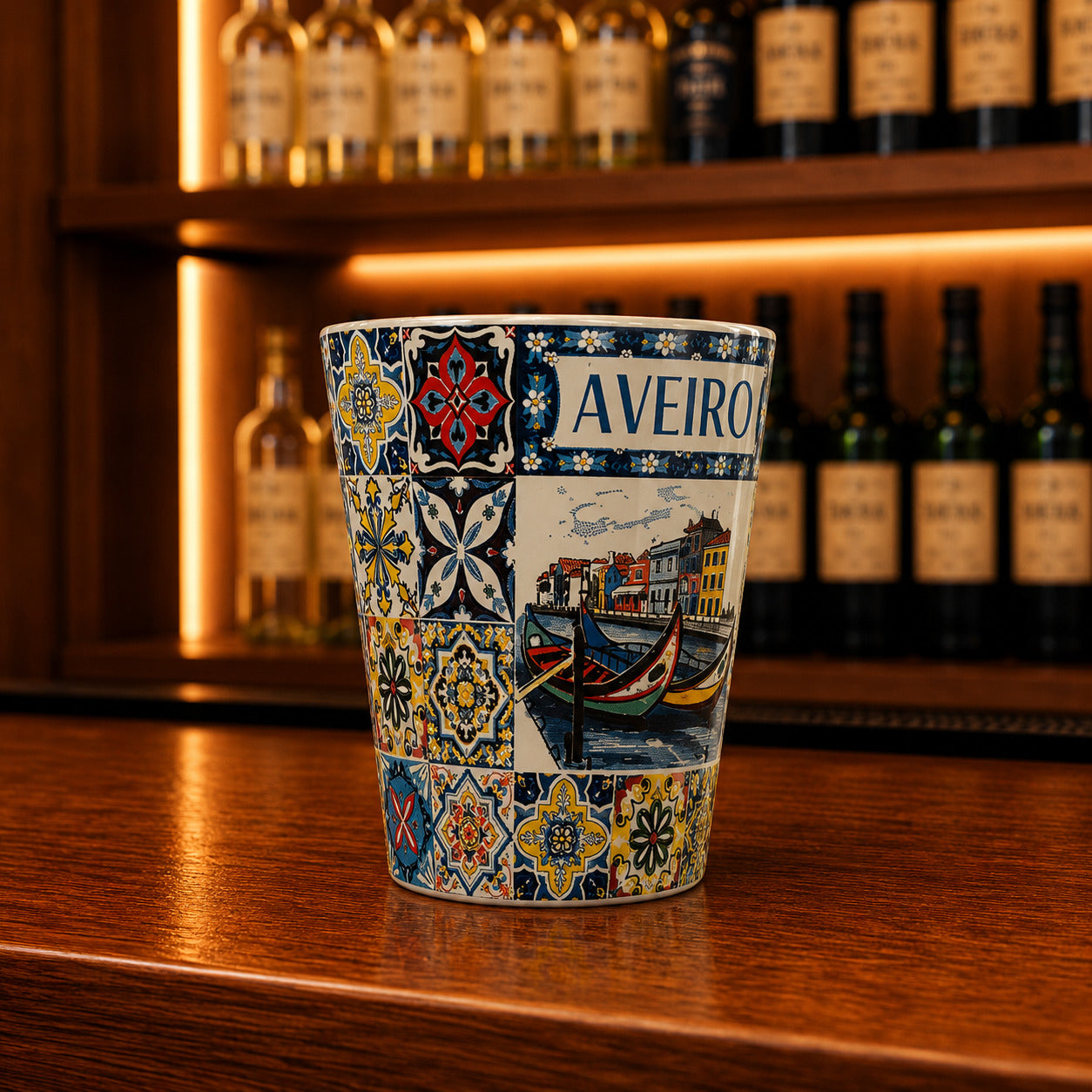 Decorative Aveiro shot glass with canal scenery, moliceiro boats, and vibrant Portuguese tile-inspired patterns on a wooden bar counter
