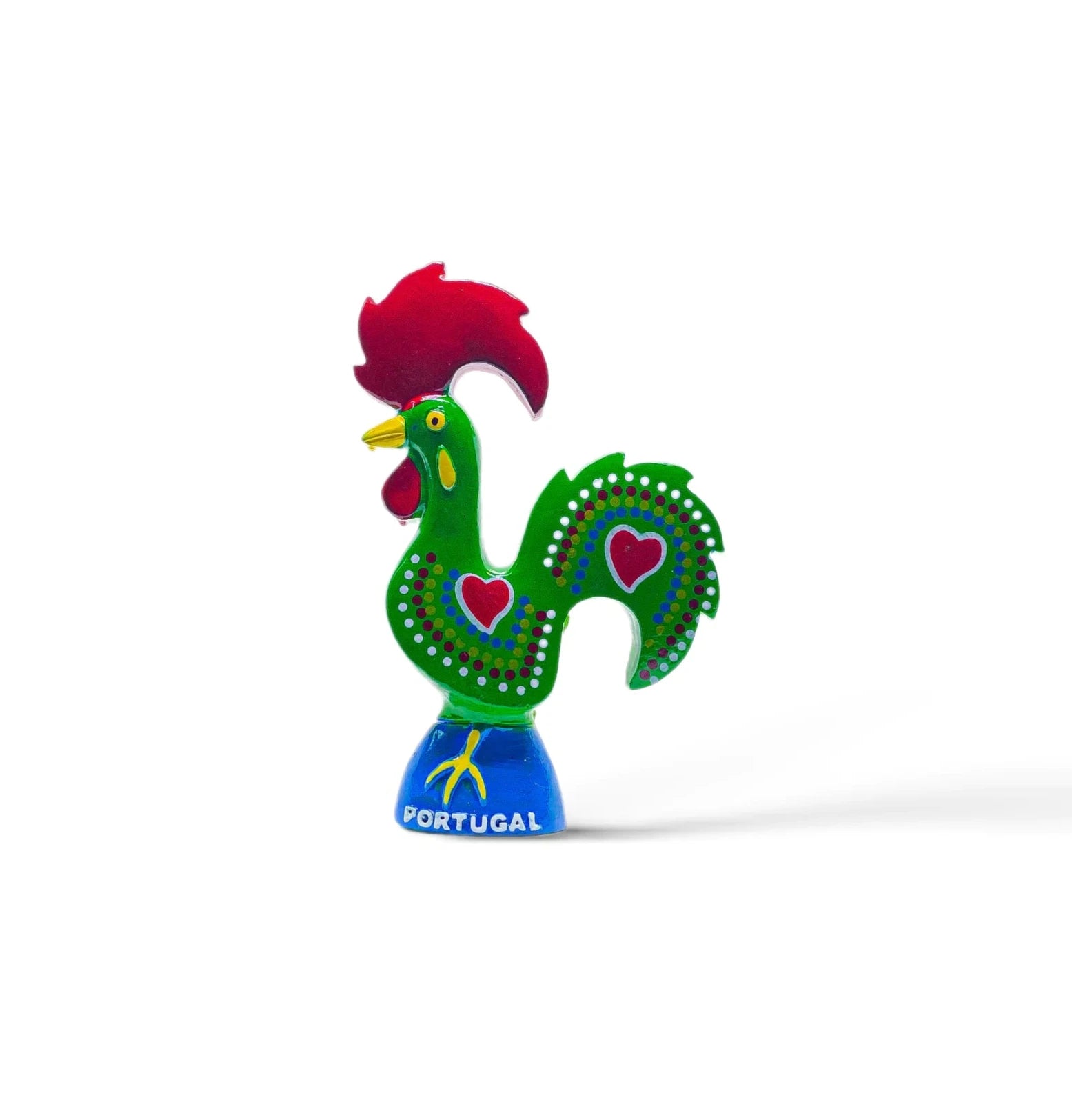 A brightly colored, decorative rooster figurine from Portugal, featuring a green body adorned with red hearts and white dots, a red comb and wattles, and a blue base with the word “Portugal” inscribed on it. This charming piece also functions as a magnet, making it an ideal souvenir.