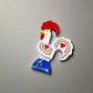 Colorful ceramic rooster figurine, the Rooster of Barcelos, a beloved symbol of Portuguese culture. It features red accents on its comb, wattle, and heart-shaped patterns on a white body, with "Portugal" on the blue base. Perfect as a decorative magnet.