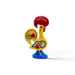 A colorful ceramic rooster figurine with intricate red, blue, and yellow patterns, standing on a blue base. The rooster has a red comb and wattle and is inscribed with the word "Portugal" on the comb, signifying it as a representation of the Galo de Barcelos. This charming piece doubles as a magnet souvenir.