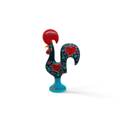 A vibrant Barcelo Rooster figurine, it boasts a black body adorned with red hearts and small white dots. With a red comb, red wattle, and standing on a blue base inscribed with "Portugal," this charming souvenir showcases intricate floral patterns.