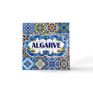 A vibrant ceramic tile magnet with "ALGARVE" boldly in the center. The tile showcases intricate blue, yellow, green, and white patterns and floral motifs, reflecting traditional Portuguese azulejos artwork. A perfect souvenir to capture the essence of Algarve.